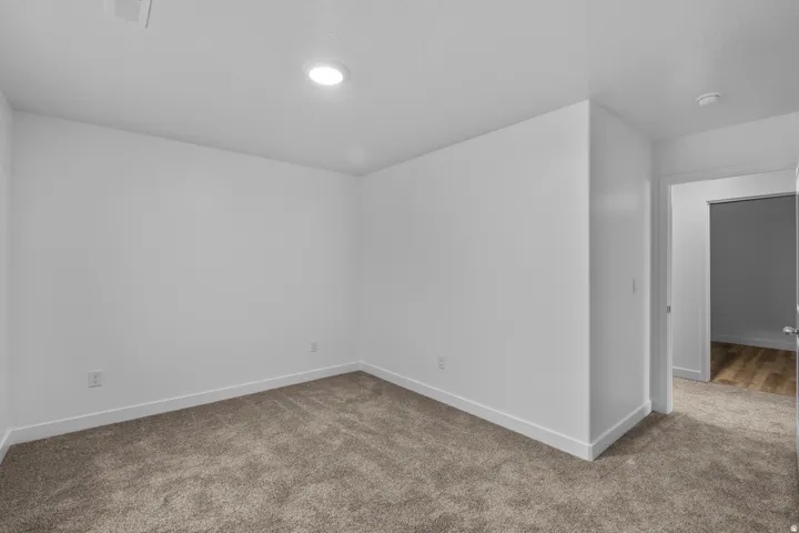 Spacious interior room featuring plush carpeting, crisp white walls, and recessed ceiling lighting