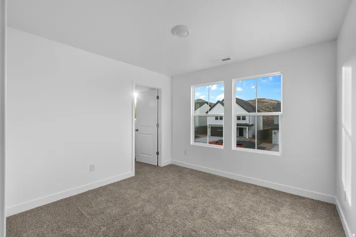 Bedroom with neutral carpet flooring, white painted walls, and white trim