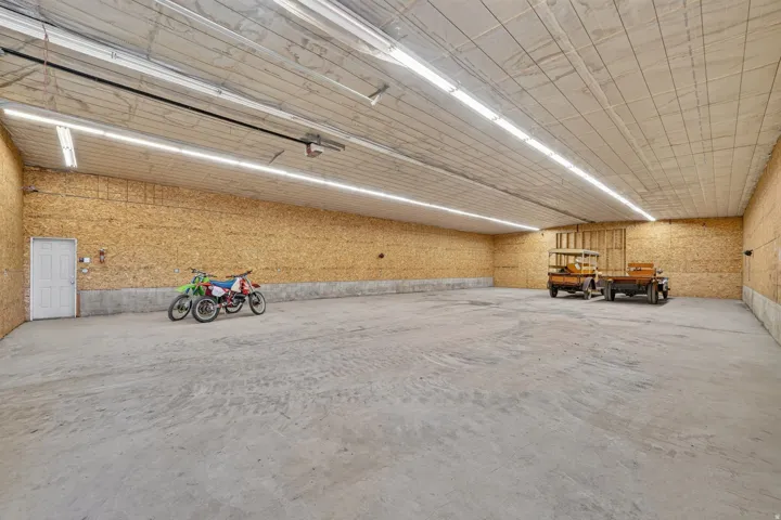 Spacious interior featuring a concrete floor, composite board walls, and a white paneled ceiling with fluorescent strip lighting