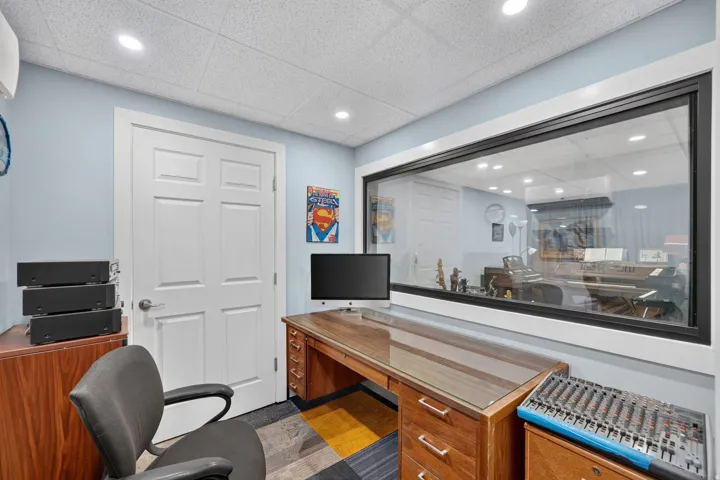Dedicated workspace featuring a large interior window, acoustical ceiling tiles, and recessed lighting
