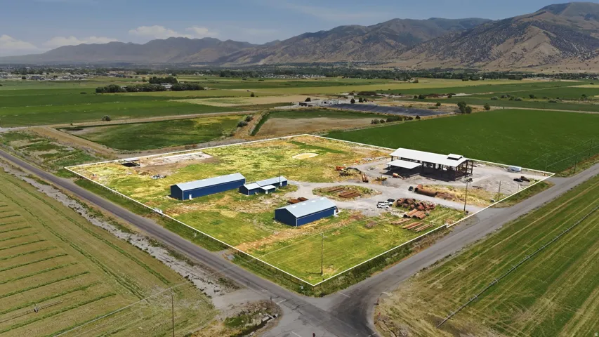 Expansive property featuring multiple outbuildings, including three blue metal structures and a larger open-frame building under construction