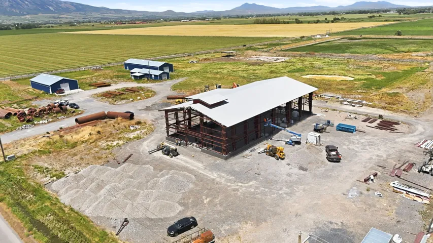 Expansive property featuring a large steel-framed structure under construction with a white metal roof