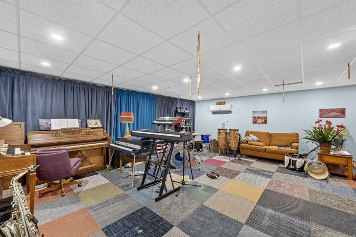 Spacious room with a drop ceiling featuring recessed lighting, light blue painted walls, and an accent wall with blue drapes