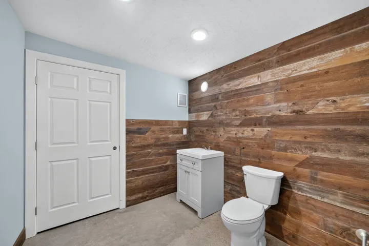 Powder room featuring a two-tone wall treatment with light blue paint and horizontal wood paneling