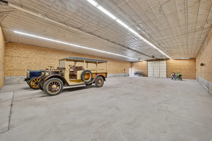 Spacious interior structure featuring high ceilings, concrete flooring, insulated walls, fluorescent lighting, and a large overhead door