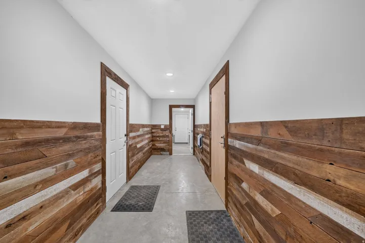Corridor featuring concrete flooring and wood-paneled wainscoting