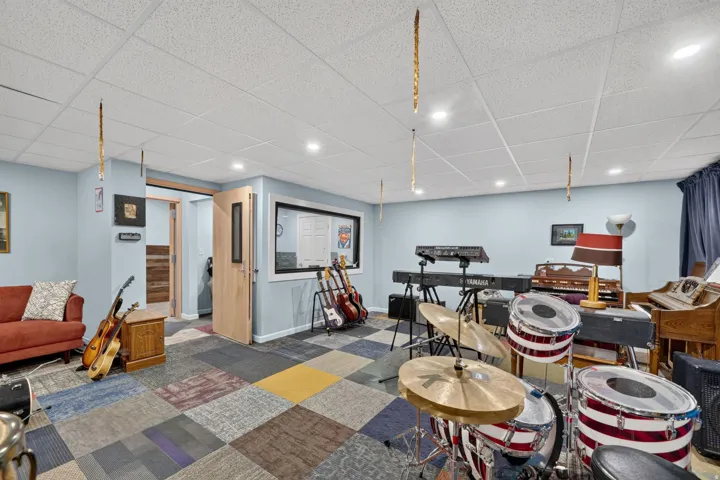 Recreation room featuring acoustic paneled doors, light blue walls, and square acoustical ceiling tiles with recessed lighting
