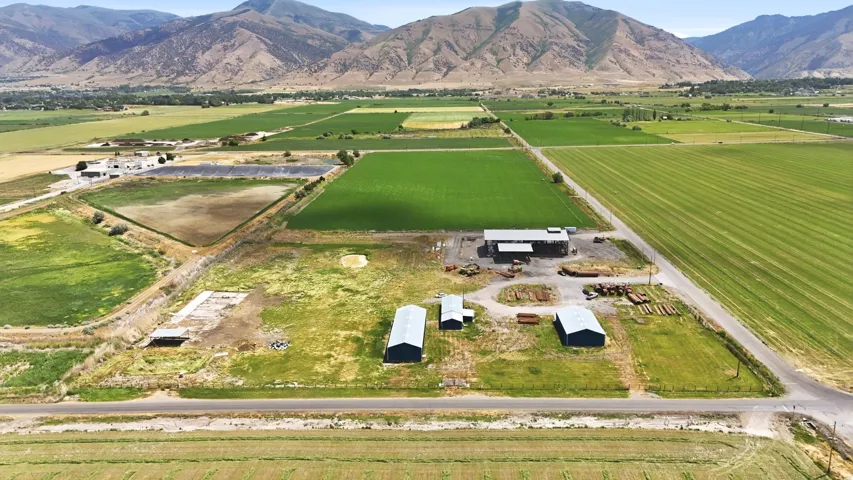 Expansive agricultural property featuring multiple outbuildings, structured fields, and a clear road frontage