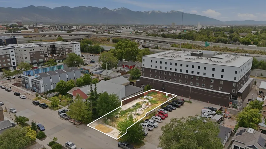 Vacant parcel featuring a surrounding street, commercial buildings, and distant mountains