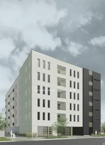 Modern multi-story building featuring a white and dark gray facade, multiple balconies with glass railings, and ground-level storefront windows