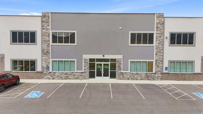Two-story commercial building featuring a stone veneer facade, multiple windows, and a paved parking lot with designated accessible parking spaces