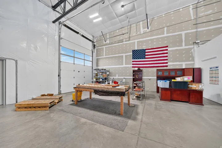 Spacious interior featuring a high ceiling, exposed structural beams, and concrete flooring