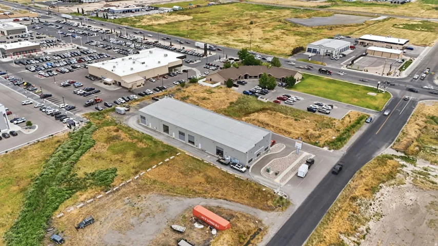 Industrial building featuring a metal roof, multiple bay doors, and a paved parking area