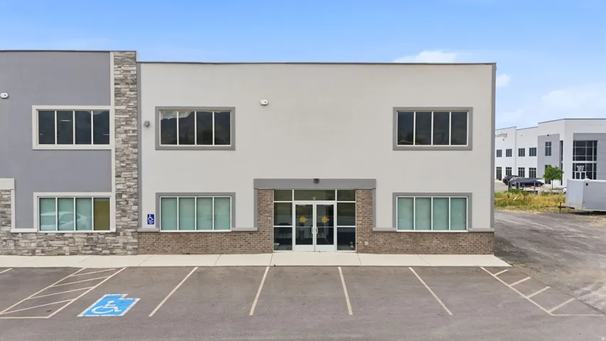 Contemporary commercial building with a mixed material facade featuring light gray stucco, darker gray stucco, and stacked stone accents