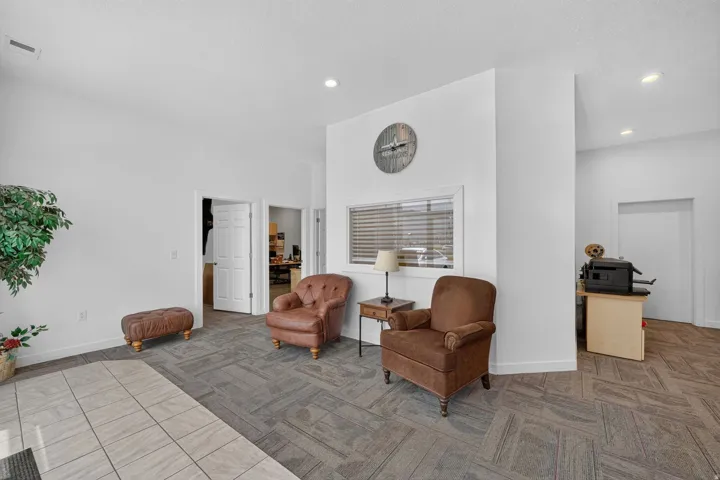Spacious interior featuring a combination of tiled and patterned carpet flooring, recessed lighting, multiple entryways, and a prominent window with blinds