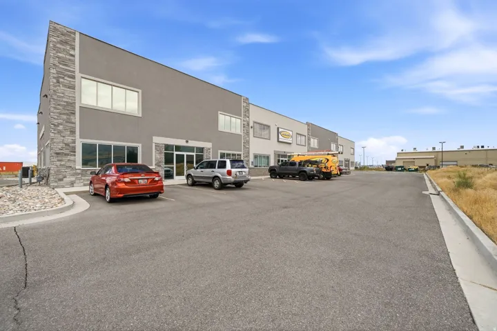 Commercial building with a stucco and stone veneer facade, multiple large windows, a double glass entry door, and an asphalt parking lot