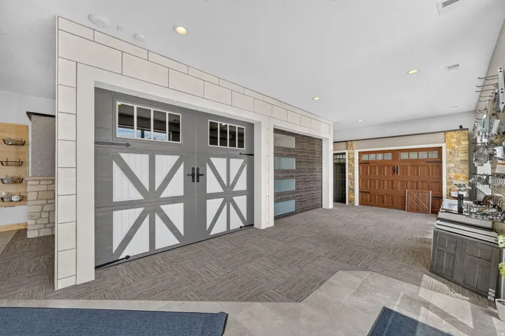 Multi-panel garage door featuring decorative hardware and upper window lites, set within a tiled wall