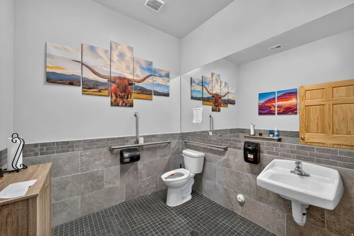 Restroom featuring a wall-mounted sink, toilet, and a full-width mirror