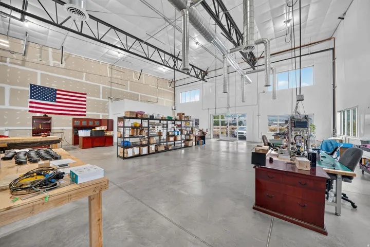 Spacious interior featuring a high ceiling, visible structural beams, polished concrete flooring, and multiple windows providing natural illumination