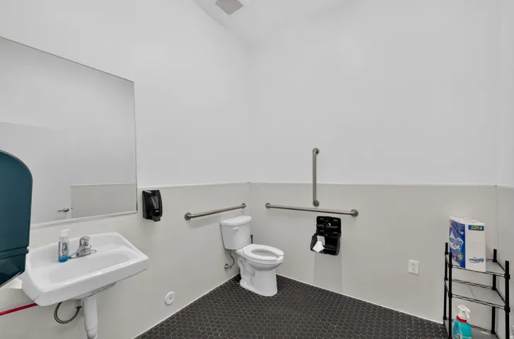Restroom featuring a wall-mounted sink, toilet, and hexagonal floor tiling