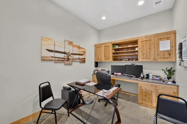 Dedicated workspace featuring custom built-in wood cabinetry, integrated shelving, and a durable countertop