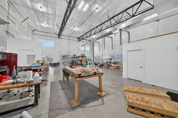Spacious industrial interior featuring a concrete floor, exposed structural beams, high ceilings, and multiple transom windows