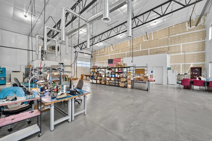 Spacious industrial interior featuring a concrete floor, exposed ceiling trusses, and extensive overhead ductwork