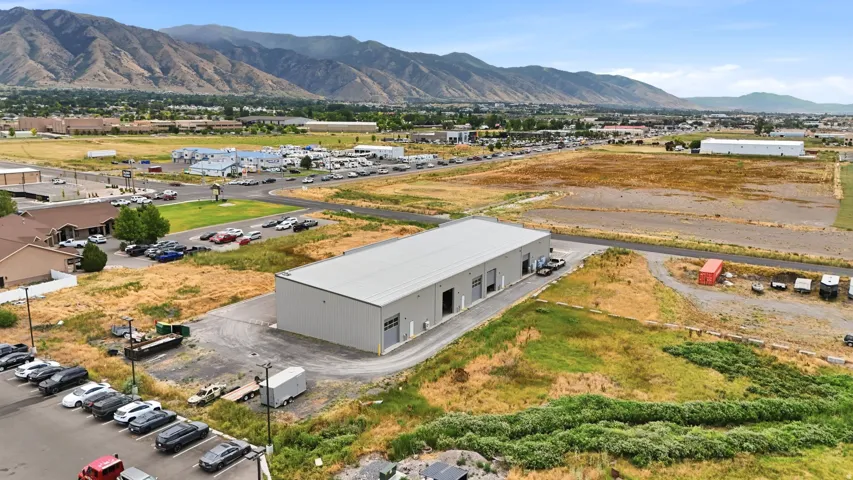 Industrial building featuring a light gray exterior, a flat roof, three bay doors, and an asphalt parking area