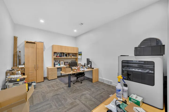 Spacious room featuring light-colored walls and recessed lighting