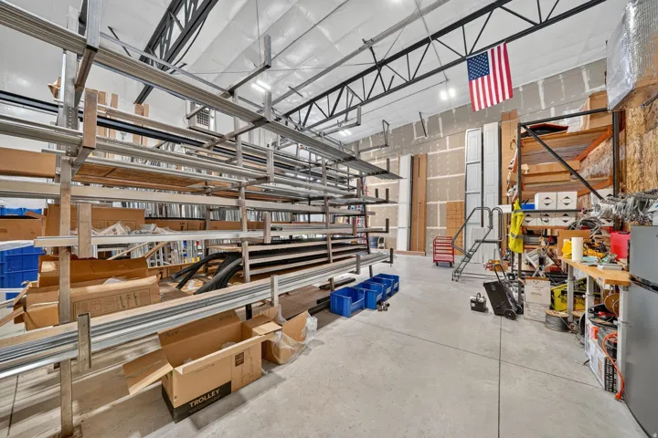 Spacious warehouse interior featuring high ceilings with exposed steel trusses, polished concrete flooring, extensive industrial racking, and ample wall space
