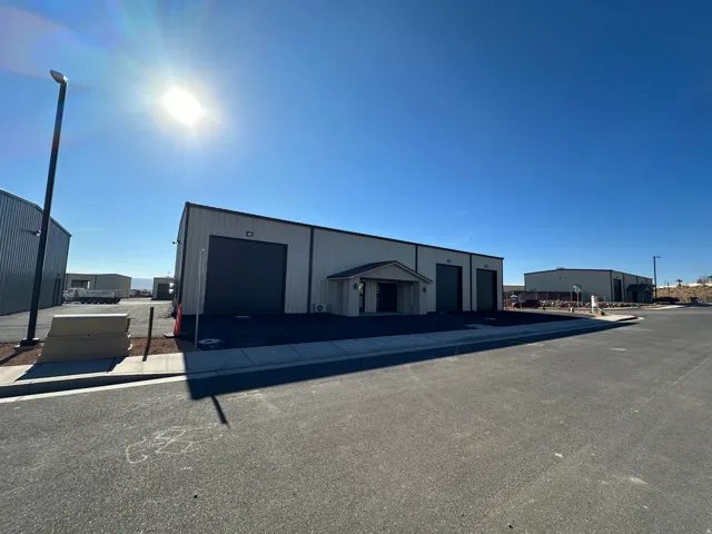 Metal-clad commercial building featuring multiple roll-up doors and a central covered entryway