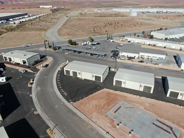 Industrial park featuring multiple buildings with roll-up doors, paved roadways, and ample parking