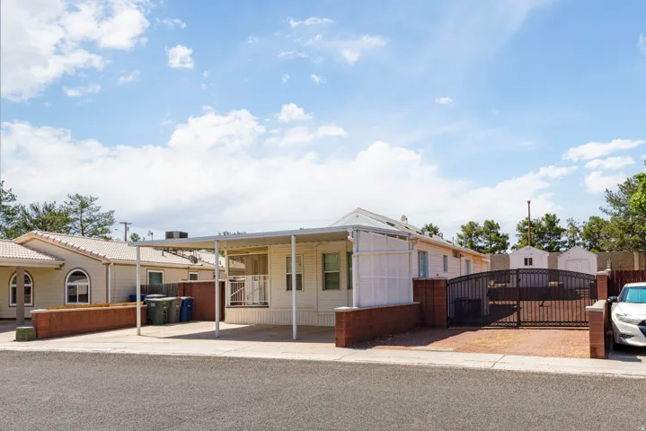 Property exterior featuring a covered carport, brick perimeter walls, and an arched metal gate