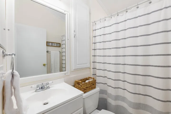 Bathroom vanity featuring a white basin sink with chrome faucet, framed mirror, and upper cabinet storage