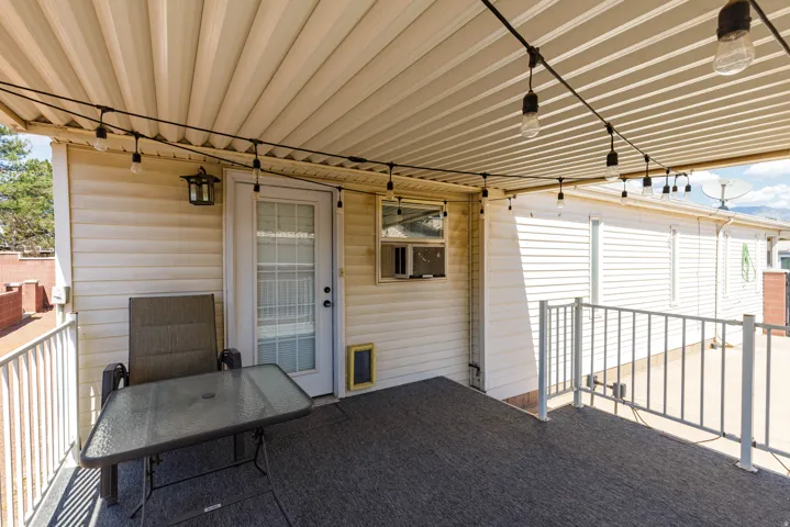 Covered patio featuring a corrugated ceiling, string lighting, and direct access through a glass-paneled door