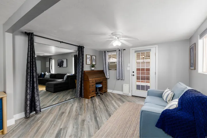 Living area featuring wood-finish flooring, a white ceiling fan, and light gray walls
