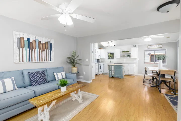 Open-concept living space featuring wood-finish flooring, white ceiling fans, and light gray wall paint