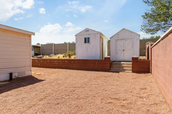 Gravel-covered yard featuring a red brick retaining wall and perimeter wall