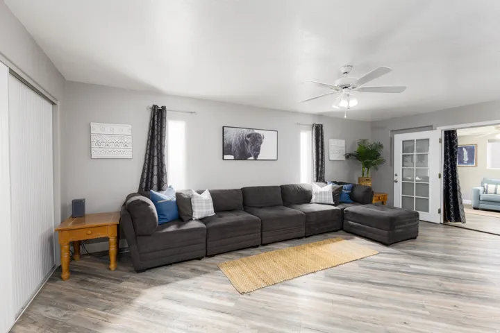 Spacious living area featuring wood-finish flooring, a ceiling fan, and light gray wall tones