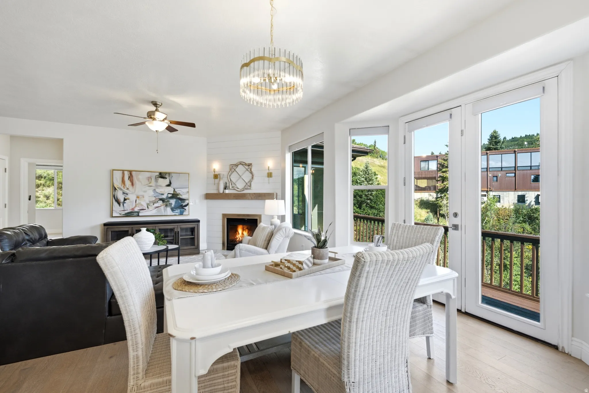 Bright dining area with wood-finish flooring, a contemporary chandelier, and French doors opening to an exterior balcony