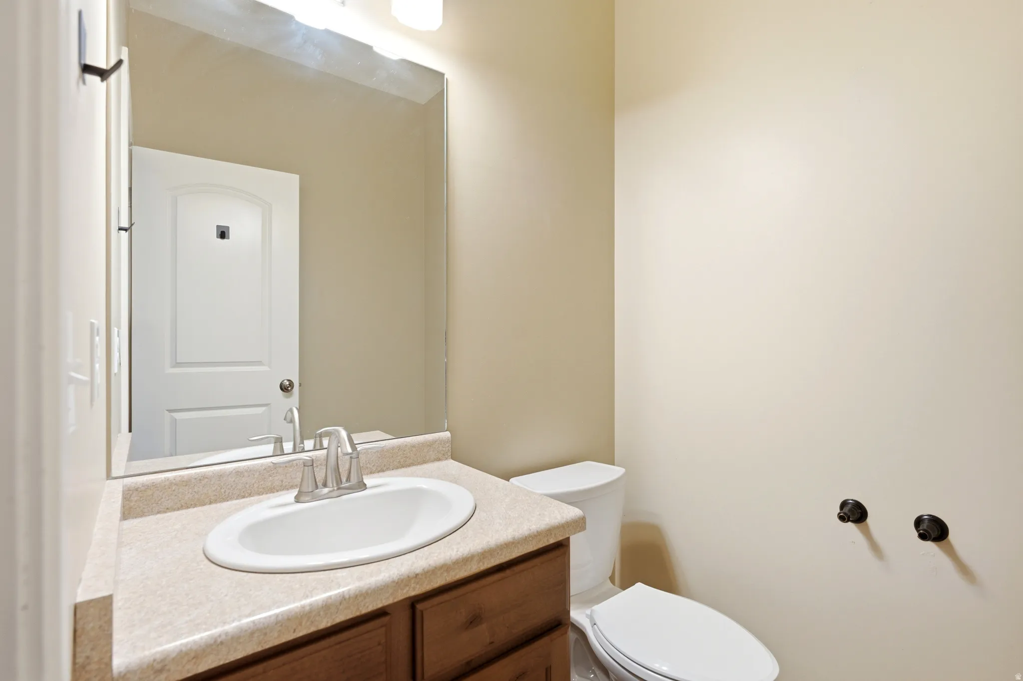 Vanity with an integrated oval sink, a chrome-finish faucet, and a large wall-mounted mirror