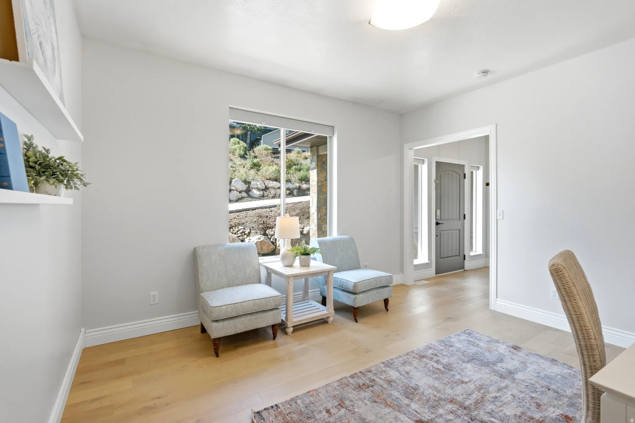 Spacious room featuring light wood-finish flooring, white baseboards, and a large window