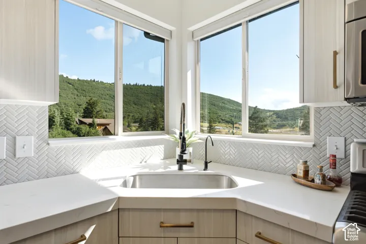 Corner kitchen sink with a stainless steel basin, contemporary black faucet, and white countertops