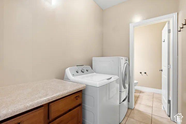 Dedicated laundry area featuring a built-in wood-finish cabinet with a light-toned countertop, and tile flooring