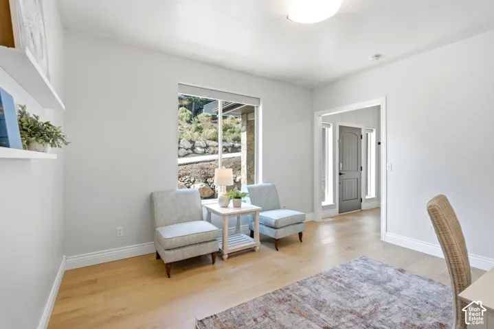 Spacious room featuring light wood-finish flooring, white baseboards, and a large window