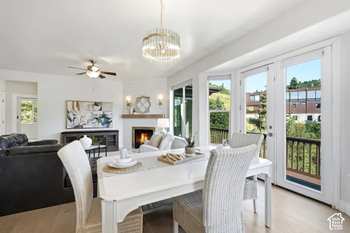 Bright dining area with wood-finish flooring, a contemporary chandelier, and French doors opening to an exterior balcony