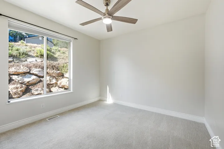Spacious room featuring light gray carpet flooring, white baseboards, and a neutral wall color