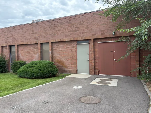 Brick exterior featuring a light gray access door and a double brown utility door