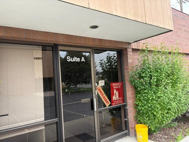 Brick exterior featuring a glass entry door with "Suite A" designation and a large adjacent window with horizontal blinds