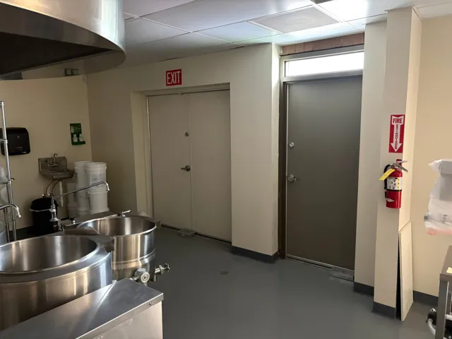 Commercial kitchen space featuring stainless steel equipment, a utility sink, and durable flooring